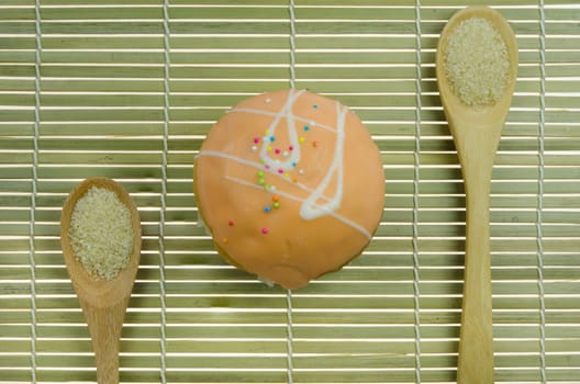 top view orange cupcake with colorful sprinkles and spoon of sugar on wooden background