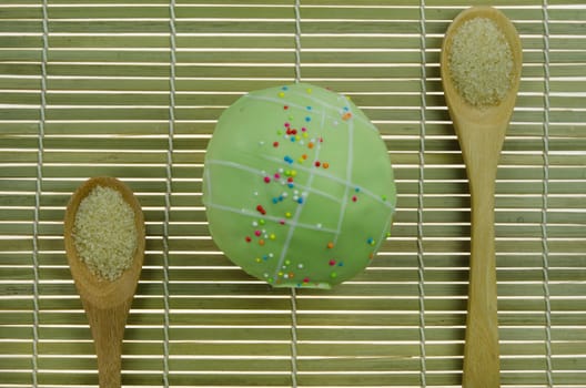 top view green cupcake with colorful sprinkles and spoon of sugar on wooden background