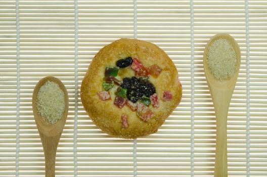 sweet bread with raisin and  dried fruits and two spoon of sugar  on wooden background