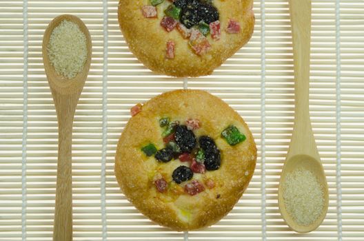 sweet bread with raisin and  dried fruits and two spoon of sugar  on wooden background