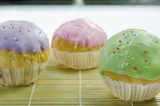 close up sweet  cupcake with colorful sprinkles on wooden board