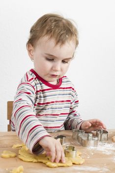 young child in vertical image looking at baking tools and dough