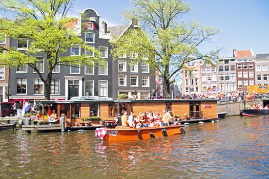 AMSTERDAM - APRIL 30: Amsterdam canals full of boats and people in orange during the celebration of queensday on April 30, 2013 in Amsterdam, The Netherlands