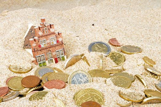 House and euro coins disappearing in the sand