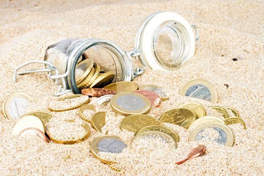 Bottle with euro coins in the sand
