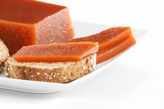 Detail of quince jam slices on seeds bread on a plate over white background.