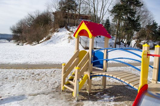 children play house with a red roof and a wooden ladder in winter