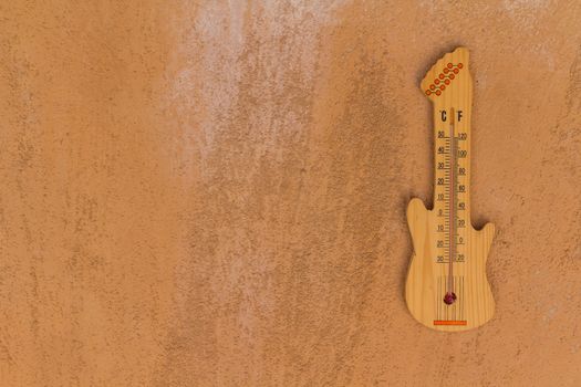 Thermometer shaped guitar on cement wall background