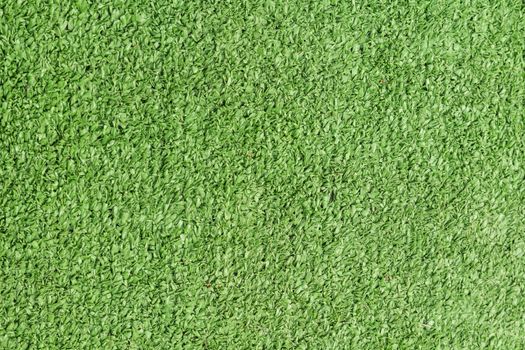 Background texture with fake grass in a public children playground, top view