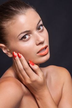 beautiful young woman with orange lipstick and brown eyes on black background