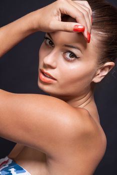 beautiful young woman with orange lipstick and brown eyes on black background