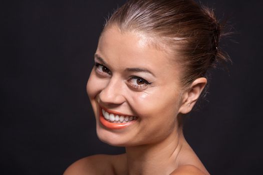 beautiful young woman with orange lipstick and brown eyes on black background