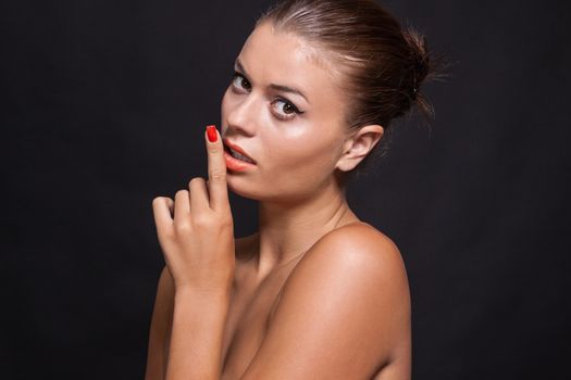 beautiful young woman with orange lipstick and brown eyes on black background