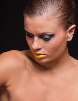 woman with extreme colorfull make up in blue and yellow on black background