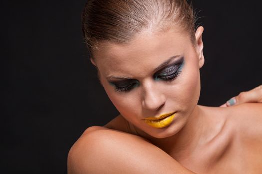 woman with extreme colorfull make up in blue and yellow on black background