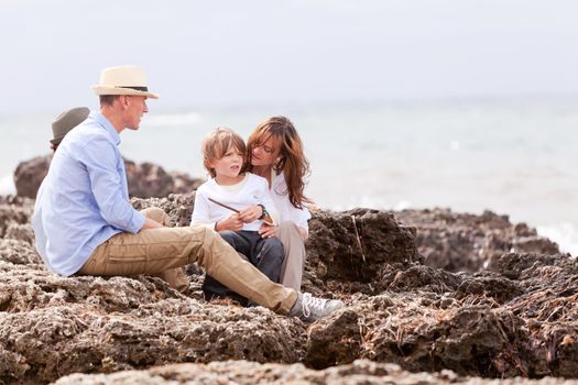 happy family sitting on rock and watching the ocean waves holiday 