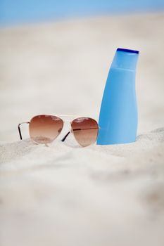 sunprotection summer holiday sunglasses and cream in sand macro