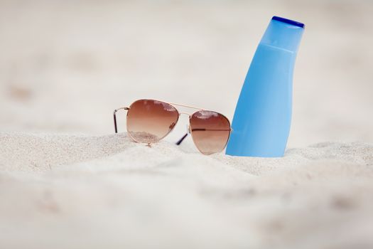 sunprotection summer holiday sunglasses and cream in sand macro
