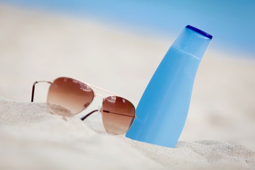 sunprotection summer holiday sunglasses and cream in sand macro