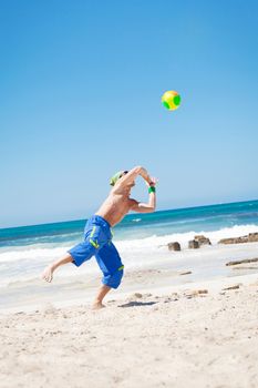 attractive young man playing volleyball on the beach summertime 