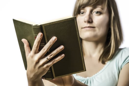 Young girl, student, holding a book and reading it, isolated on white background