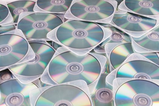 Reflective side of DVDs in hard clear plastic cases strewn about carelessly.