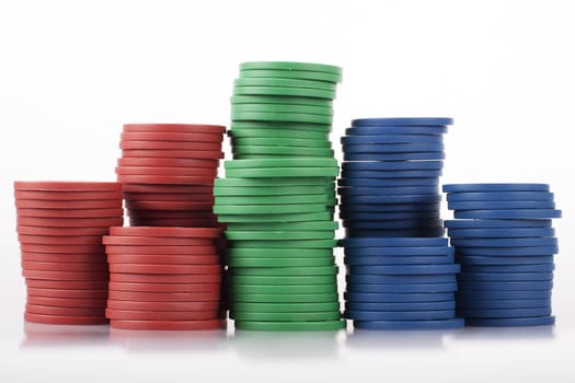 Red, green, blue plastic poker chips from the side on white with reflection.