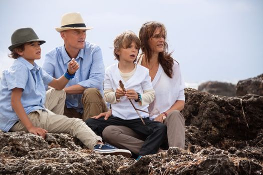 happy family sitting on rock and watching the ocean waves holiday 