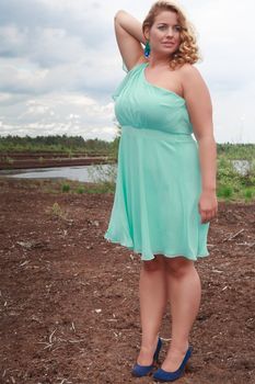 Thick young girl in summer dress elegant aquamarine in the steppe