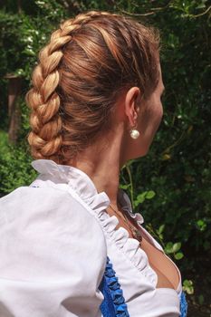 Portrait of a young woman in dirndl with traditional plaits