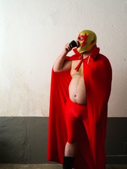 Photograph of a Mexican wrestler or Luchador drinking coffee before his fight.
