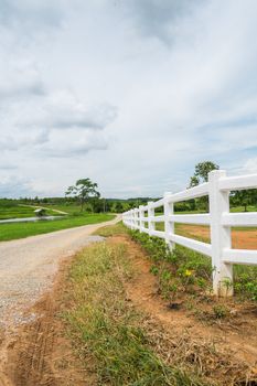 white fence in farm field and overcast sky