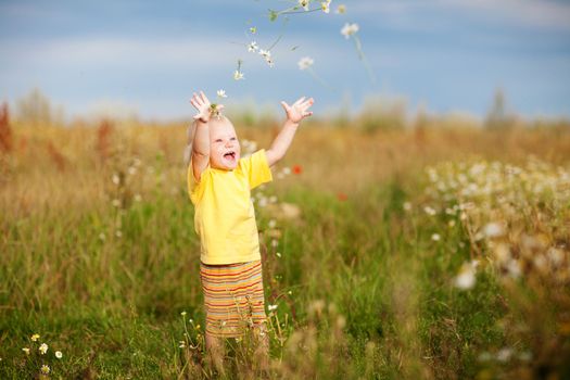 child throwing flowers on the field