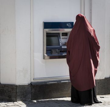 Unidentified muslim woman seen from behind by cashpoint.
