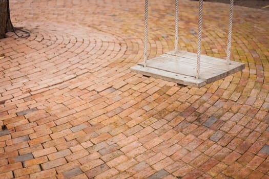 Swing wood in playground with brick floor