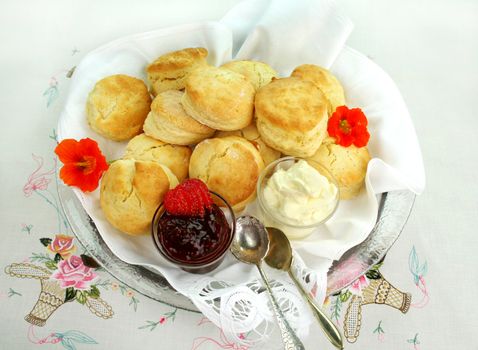 Plate of fresh baked scones with cream and strawberry jam ready to serve.