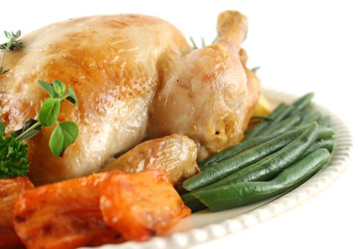 Whole roast chicken with potatoes pumpkin carrots and beans.