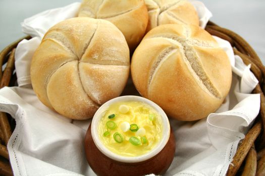 Fresh round breadrolls with a jar of butter and diced spring onions.