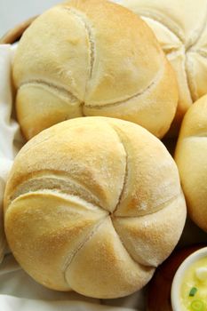 Fresh round breadrolls with a jar of butter and diced spring onions.