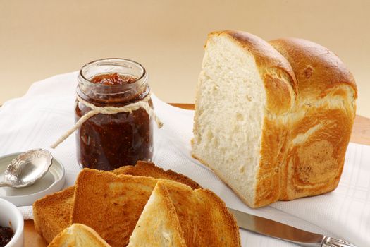 Jar of homemade fig jam with a loaf of crusty bread.