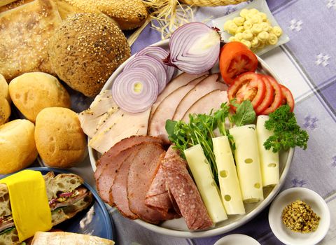 Platter full of fresh ingredients to make sandwiches along with selection of breads.