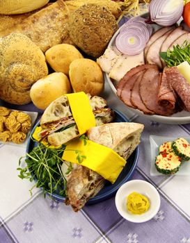 Platter full of fresh ingredients to make sandwiches along with selection of breads.