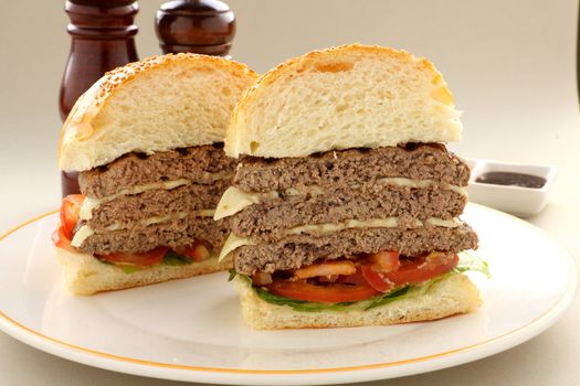 Sliced triple decker beef and cheese burger with salad ready to serve.