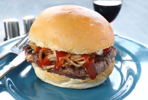 Freshly prepared fillet steak burger with fried onions and ketchup