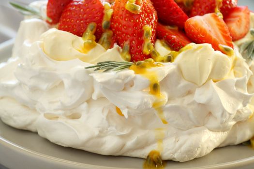 Pavlova with fresh strawberries and passionfruit ready to serve.
