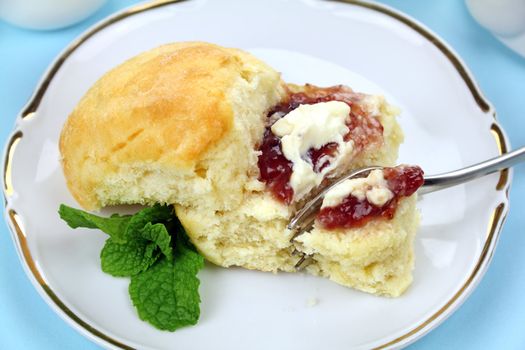 Fresh baked scone with jam and cream ready to serve.