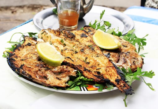 Grilled fish with greens on the plate
