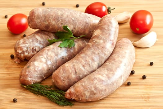 Uncooked sausages with vegetables on the chopping board
