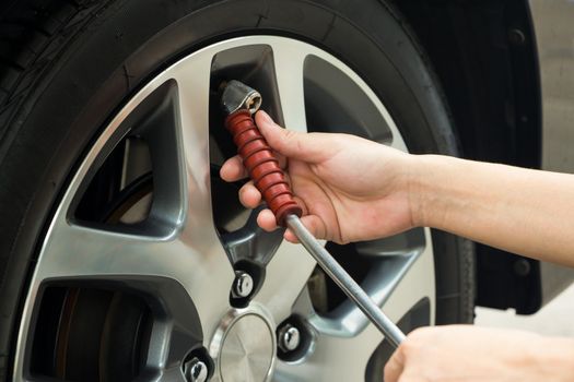 Hand fill air into a car tire.