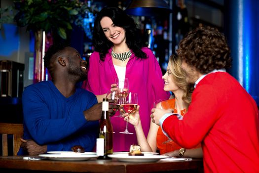 Two young couples in club or bar raising a toast.